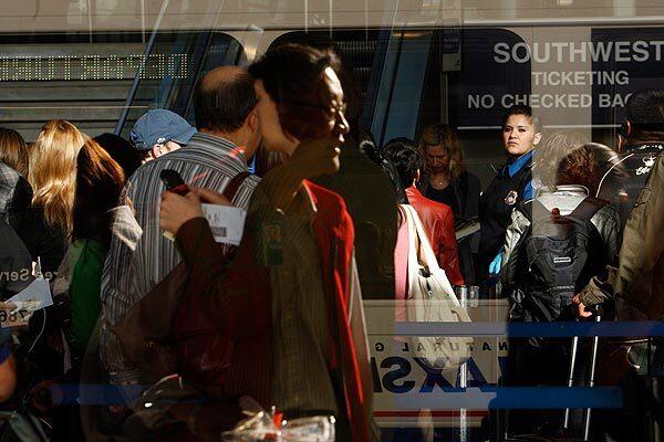 A TSA agent looks out at Thanksgiving travelers as they make their way through the Los Angeles International Airport Wednesday morning.