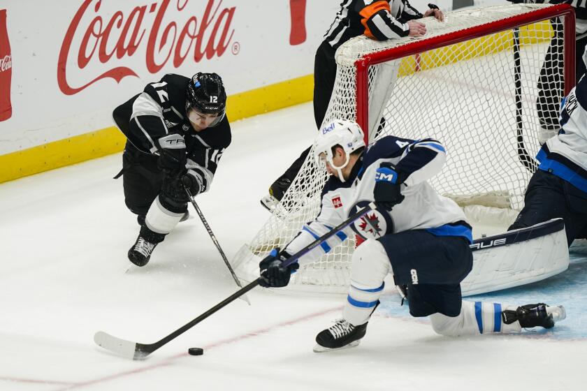 Los Angeles Kings left wing Trevor Moore, left, loses the puck to Winnipeg Jets defenseman Neal Pionk during the third period of an NHL hockey game, Wednesday, Dec. 13, 2023, in Los Angeles. (AP Photo/Ryan Sun)