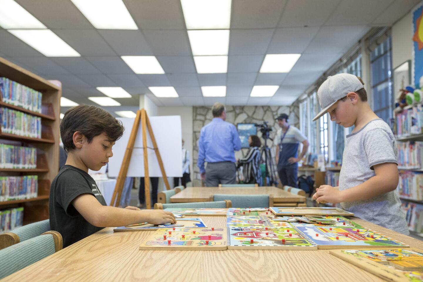 Benjamin Boone, 7, left, and Gavin Laubach, 7, play with puzzles during a farewell party at the Corona del Mar Branch Library on Wednesday, March 14.