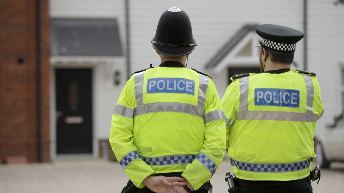 British police officers stand facing a residential property in Amesbury, England, on July 4 after two people were exposed to an unknown substance.