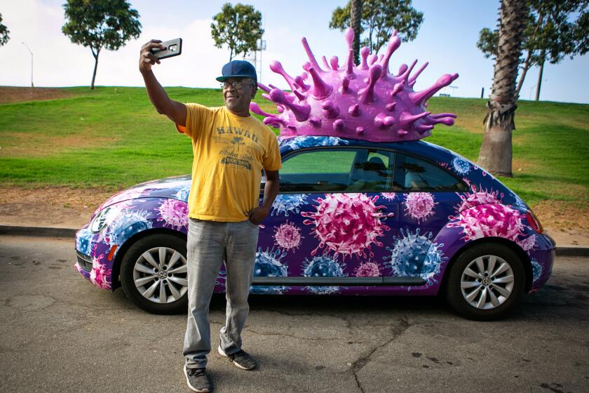 EL SEGUNDO, CA - JUNE 27: Aaron Sanderlin of Inglewood takes a selfie by a Volkswagen Covid-19 car on Sunday, June 27, 2021 in El Segundo, CA. (Jason Armond / Los Angeles Times)