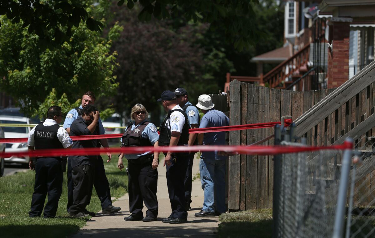 Chicago police officers talk with a man near where a father was shot in the Brighton Park neighborhood Thursday.