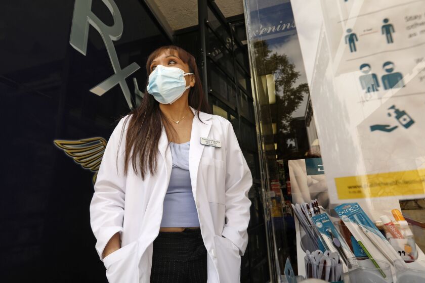 San Pedro, California-FEb. 10, 2021-Hanh Duong, a pharmacist at Peninsula Pharmacy in San Pedro, wears a double mask when dealing with customers. "We plan to adhere to that (the new recommendations.) Being in a small space with co-workers, she says it's important to keep a mask on even though she has been vaccinated. The Center for Disease Control has now issued a recommendation saying that two masks better protect us against COVID-19. Wearing a cloth mask over a medical procedure mask can significantly decrease the spread of COVID-19, according to a new study the Centers for Disease Control and Prevention (CDC) released Wednesday. The agency updated its guidance to note that double masking or wearing a tightly fitted surgical mask are two of the best ways to boost protection against exposure. (Carolyn Cole/Los Angeles Times)