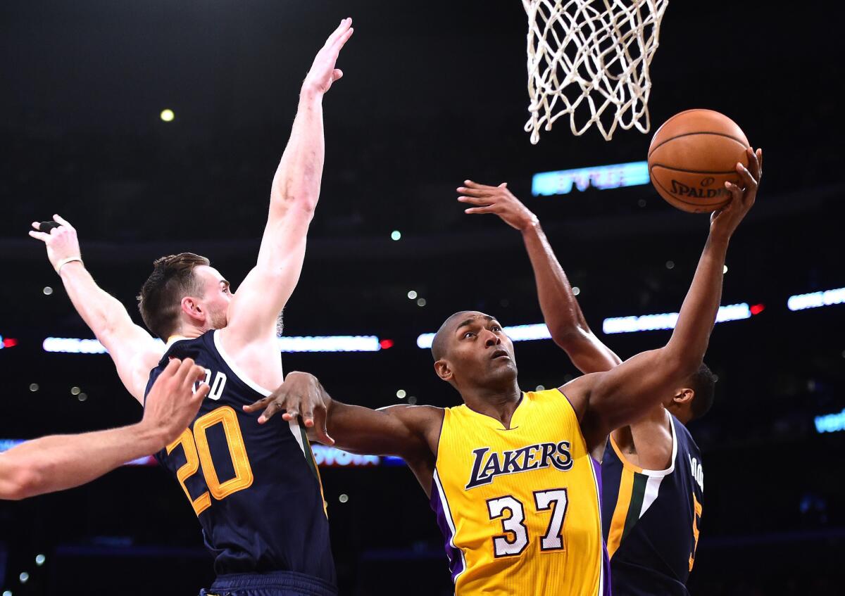 Lakers forward Metta World Peace (37) scores between Jazz defenders Gordon Hayward (20) and Rodney Hood (5) during the first half on Dec. 5.