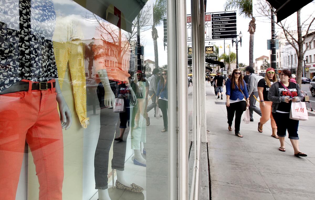 Shoppers pass by a store window on Colorado Boulevard in Pasadena on March 6, 2013.