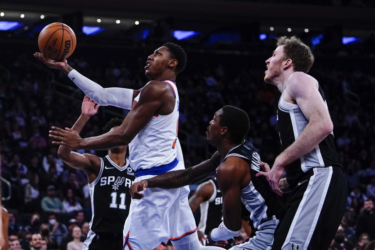 New York Knicks' RJ Barrett, front left, drives past San Antonio Spurs' Joshua Primo (11), Lonnie Walker IV, second from right, and Jakob Poeltl, right, of Austria, during the second half of an NBA basketball game Monday, Jan. 10, 2022, in New York. (AP Photo/Frank Franklin II)