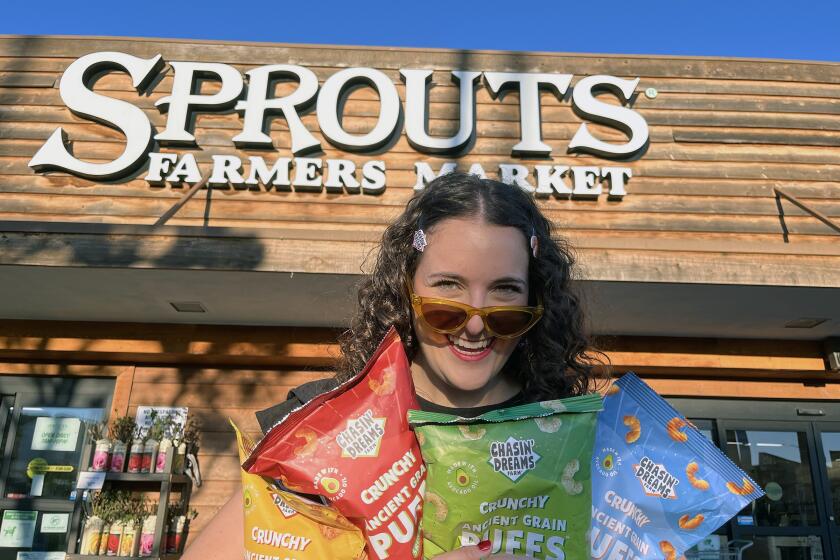 Sydney Chasin, CEO of Chasin' Dreams Farms holds bags of her snacks outside of Sprouts Farmers Market.