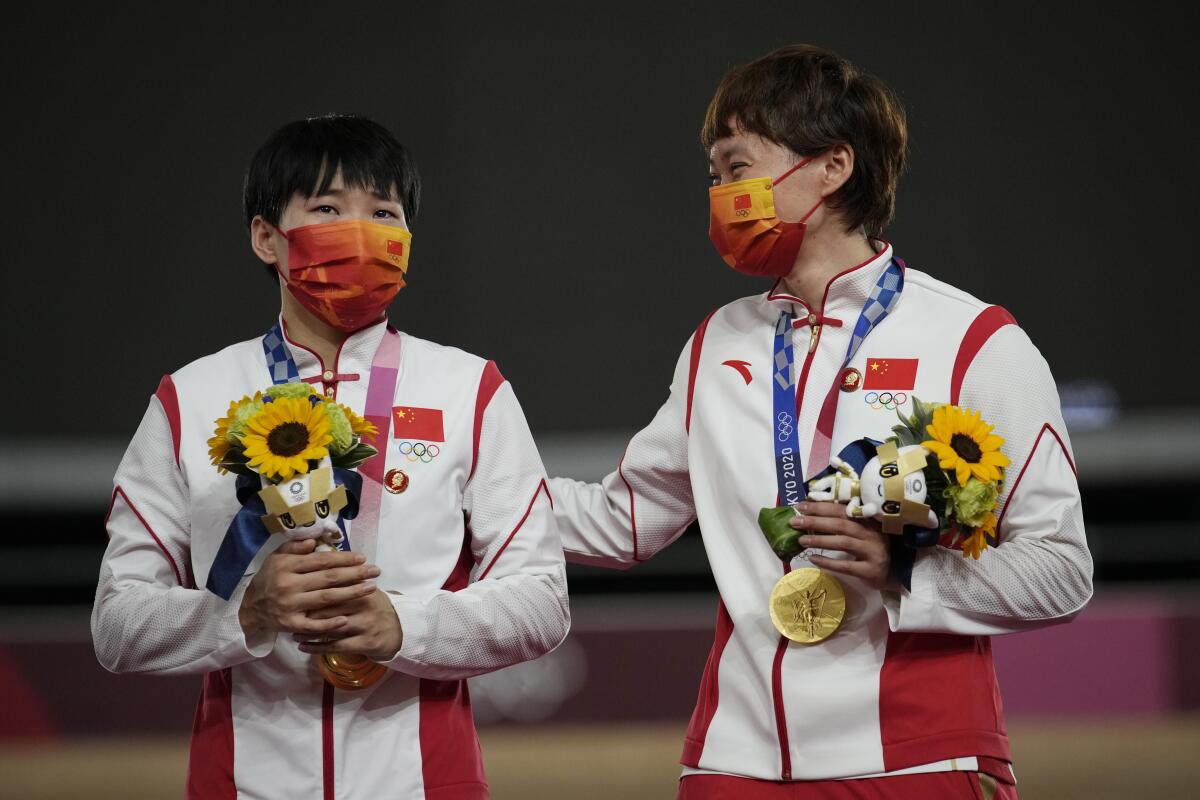Shanju Bao, left, and Tianshi Zhong, of China, celebrate their gold medals during a ceremony for the track cycling women's team sprint finals at the 2020 Summer Olympics, Monday, Aug. 2, 2021, in Izu, Japan. (AP Photo/Christophe Ena)