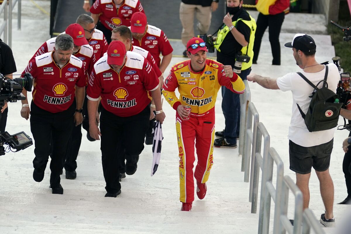 Joey Logano, second from right, bumps fists with a fan as he walks up to Victory Lane with his crew after winning a NASCAR exhibition auto race at Los Angeles Memorial Coliseum, Sunday, Feb. 6, 2022, in Los Angeles. (AP Photo/Marcio Jose Sanchez)