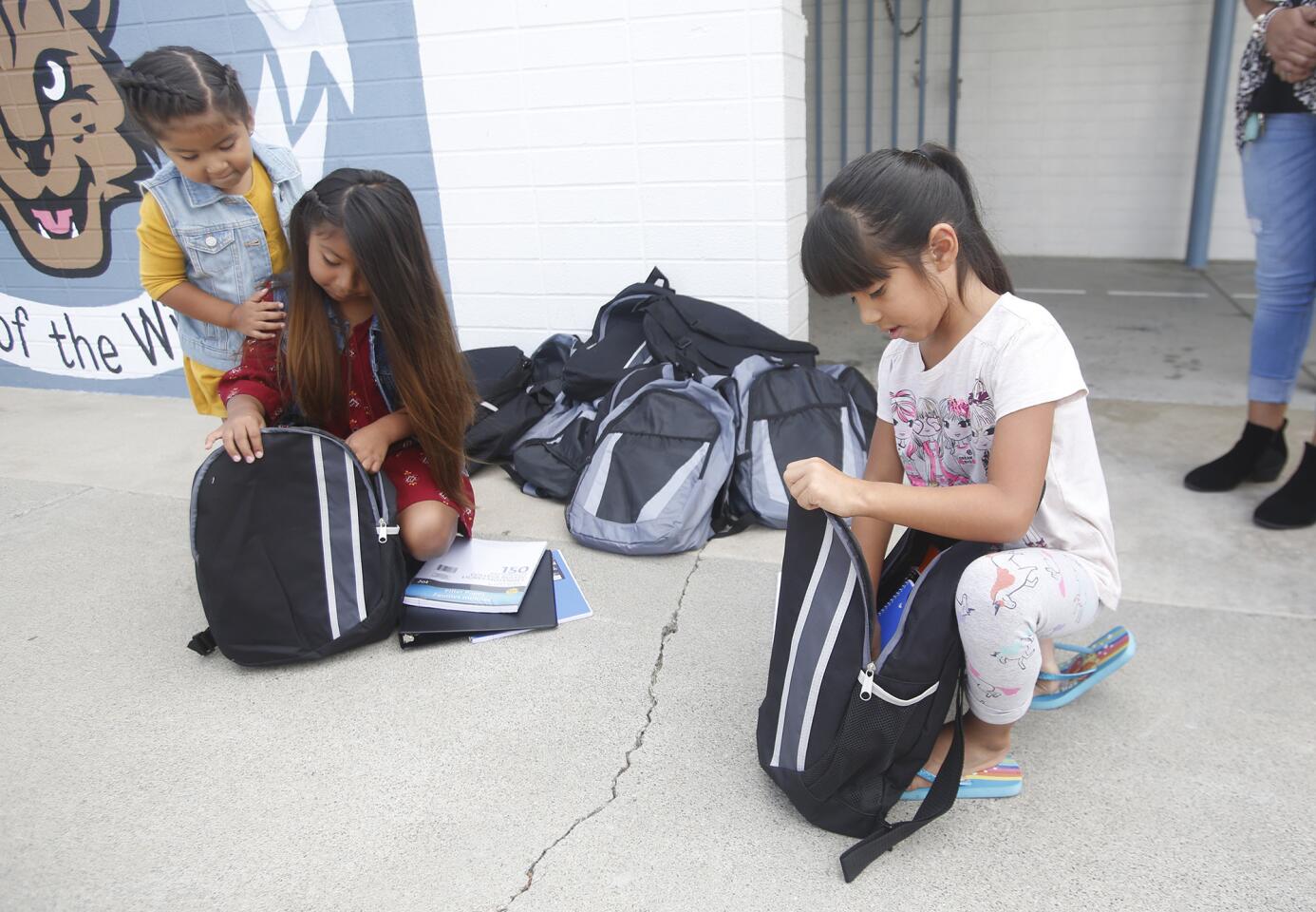 Audrey Flores, left, and Kelsey Caiutce pull school supplies from their new backpacks Tuesday at College View Elementary School in Huntington Beach. The backpacks were donated by OnTrac, an Arizona-based package delivery company.