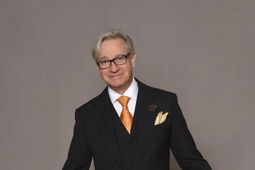 A man in a black suit and orange tie