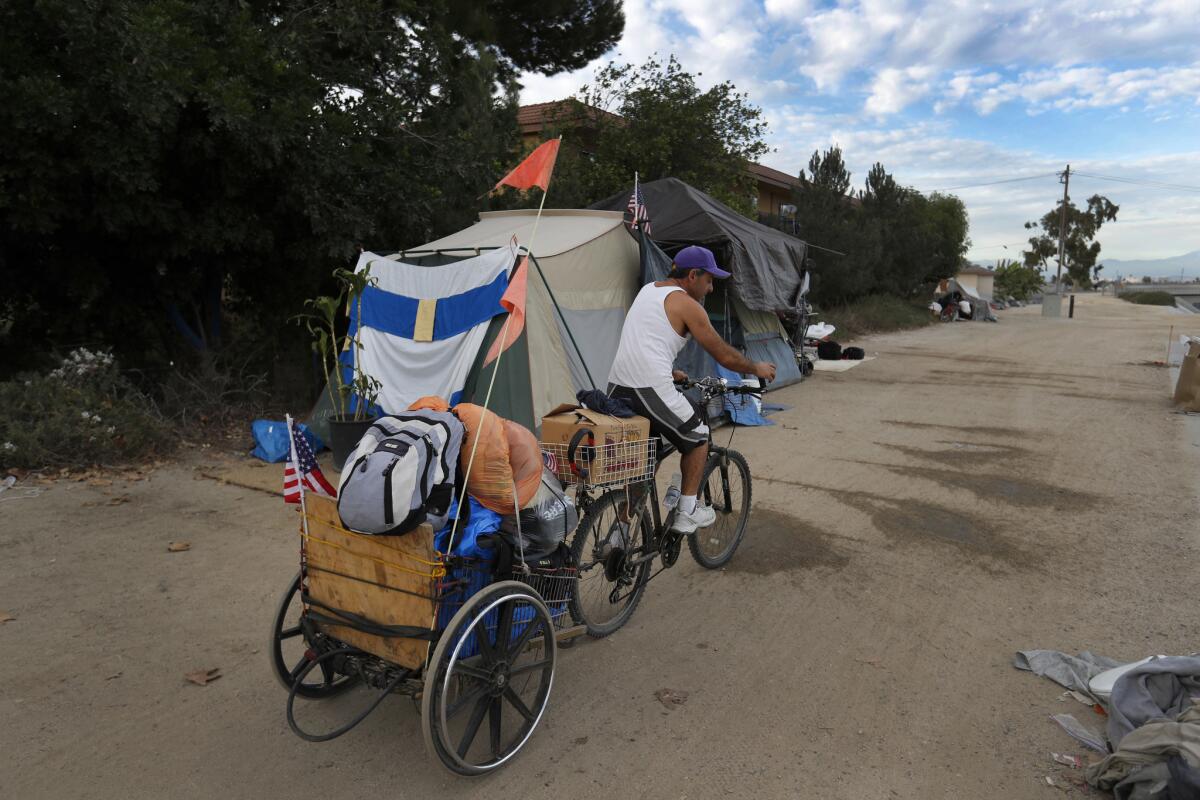 A homeless man packs up his tents and leaves the Santa Ana River camp before the eviction begins.
