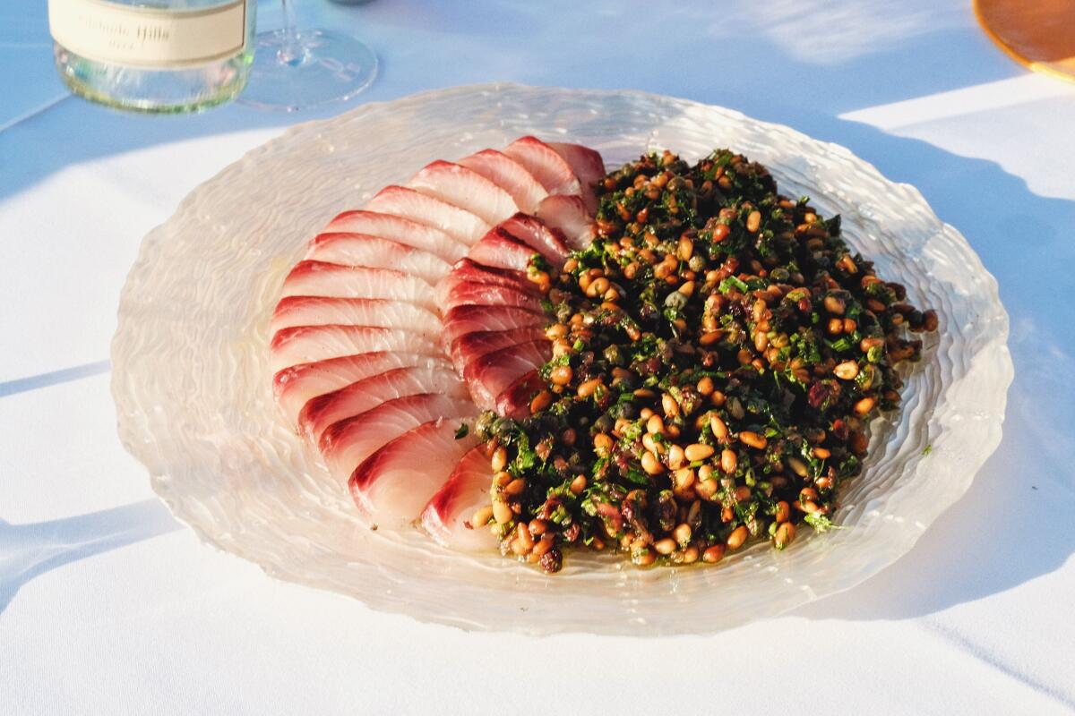 A plate of sliced hiramasa with fig leaf and pine nut salad.