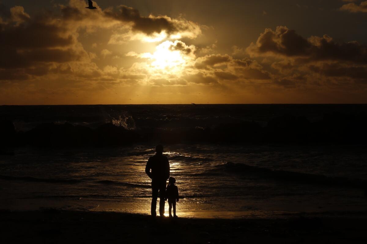 Niklas Hofverberg and his daughter Bianca watch the sun set as storm clouds dissipate in Venice on Monday.