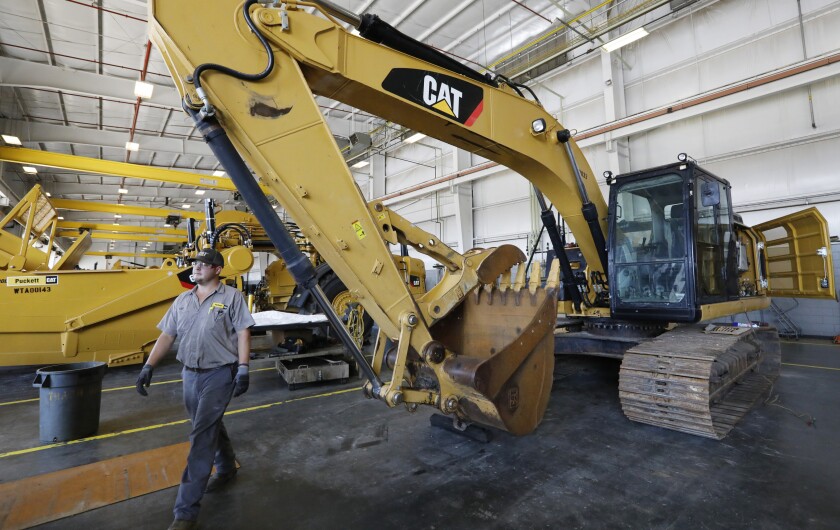 FILE - A Puckett Machinery Company technician walks past a new heavy duty Caterpillar excavator that awaits modification at Puckett Machinery Company in Flowood, Miss. Sept. 18, 2019. Caterpillar continued to see a healthy surge in sales during its fourth quarter of 2022, as the economy strengthens. Sales climbed 23% to $13.8 billion. (AP Photo/Rogelio V. Solis)
