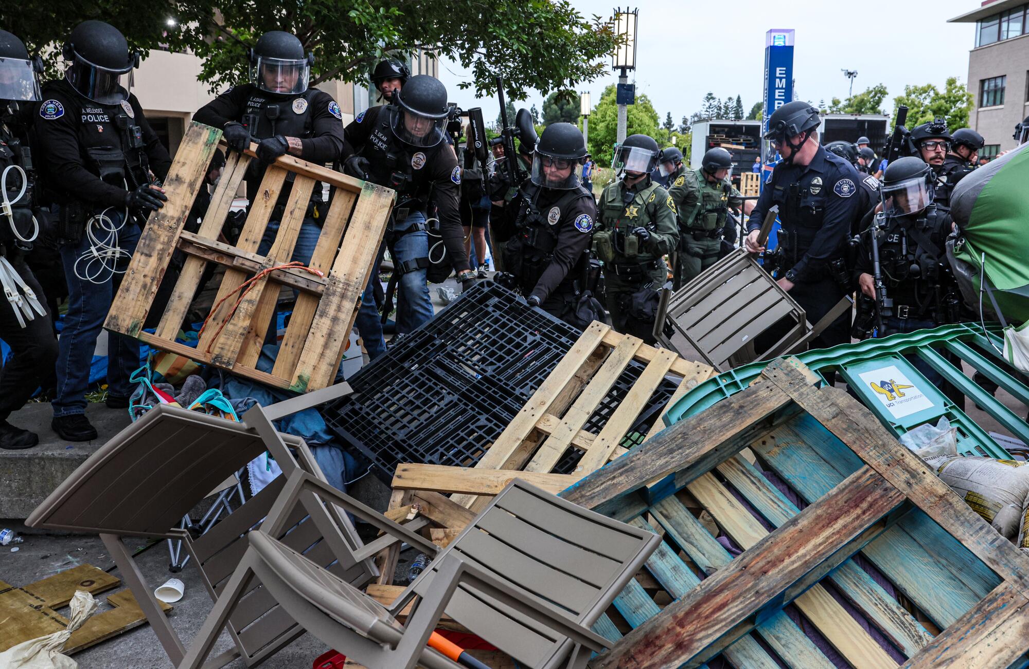 Police remove pallets and furniture set up as a barricade.