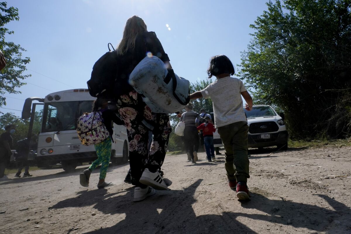 ARCHIVO - Una familia de migrantes venezolanos se dirige hacia un autobús de la Patrulla Fronteriza