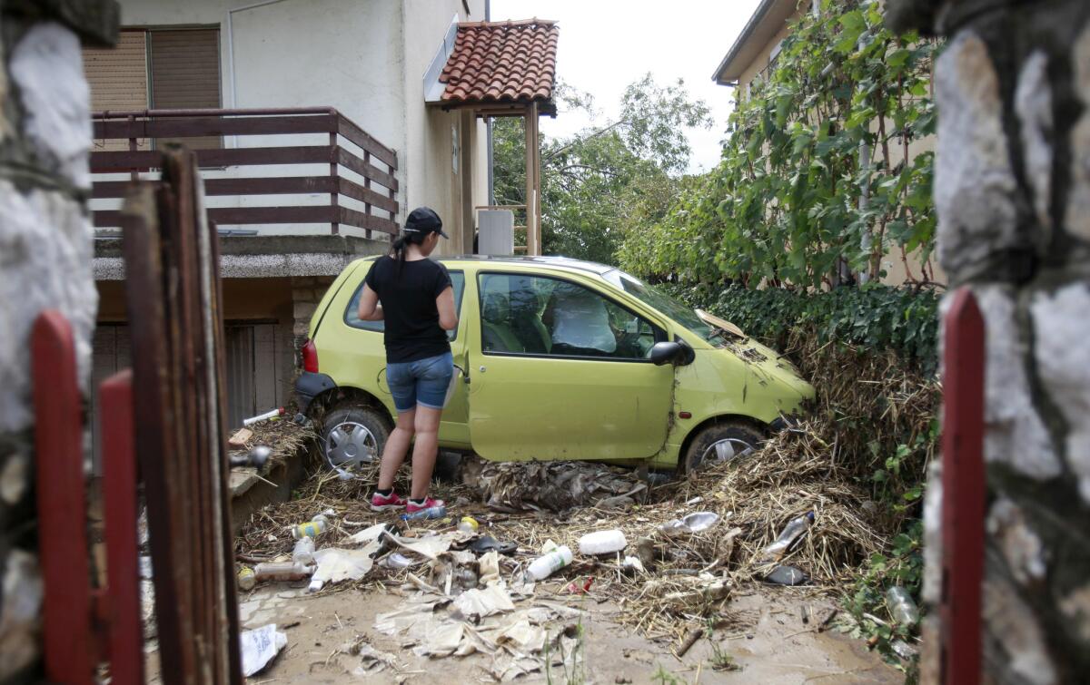 Una mujer observa un vehículo dañado en el patio de una casa después de que se retiraran las inundaciones en la aldea de Stajkovci, al este de Skopie, capital de Macedonia, el lunes 8 de agosto de 2016. El gobierno de Macedonia declaró el domingo el estado de emergencia en partes de la capital castigadas por los aguaceros y las inundaciones, las cuales dejaron numerosas personas muertas, según las autoridades. (AP Foto/Boris Grdanoski)