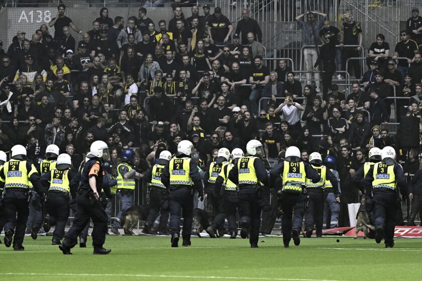 Police officers holding off AIK supporters trying to enter the pitch during the Allsvenskan soccer match between Djurgarden's IF and AIK at Tele2 Arena in Stockholm, Sweden, Sunday May 28, 2023. The Swedish government called an emergency meeting of the country’s soccer federation on Monday after crowd disorder during a match between Stockholm rivals AIK and Djurgardens that caused a one-hour delay. (Jonas Ekströmer/TT News Agency via AP)
