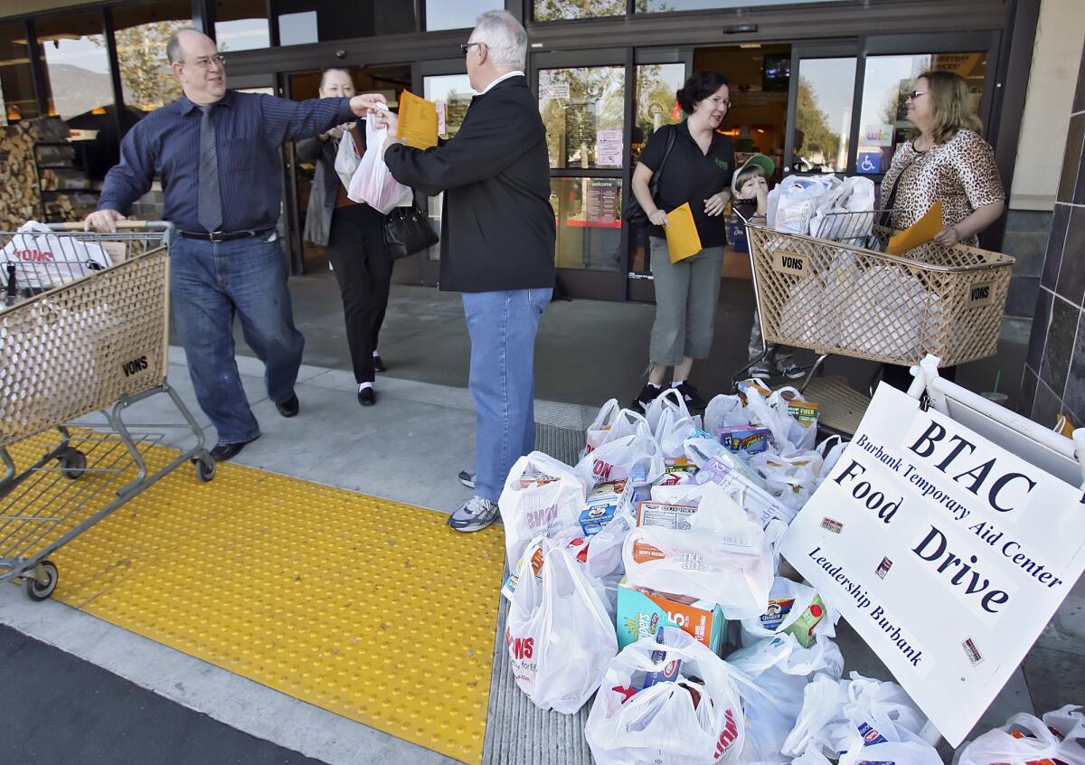 Peter Beckman, left, donates groceries to Leadership Burbank alumni Barry Gussow who helps collect groceries for the Burbank Temporary Aid Center at the Burbank Pavilions. The agency is one of a few that received a bump in funding from the City Council through a state grant.