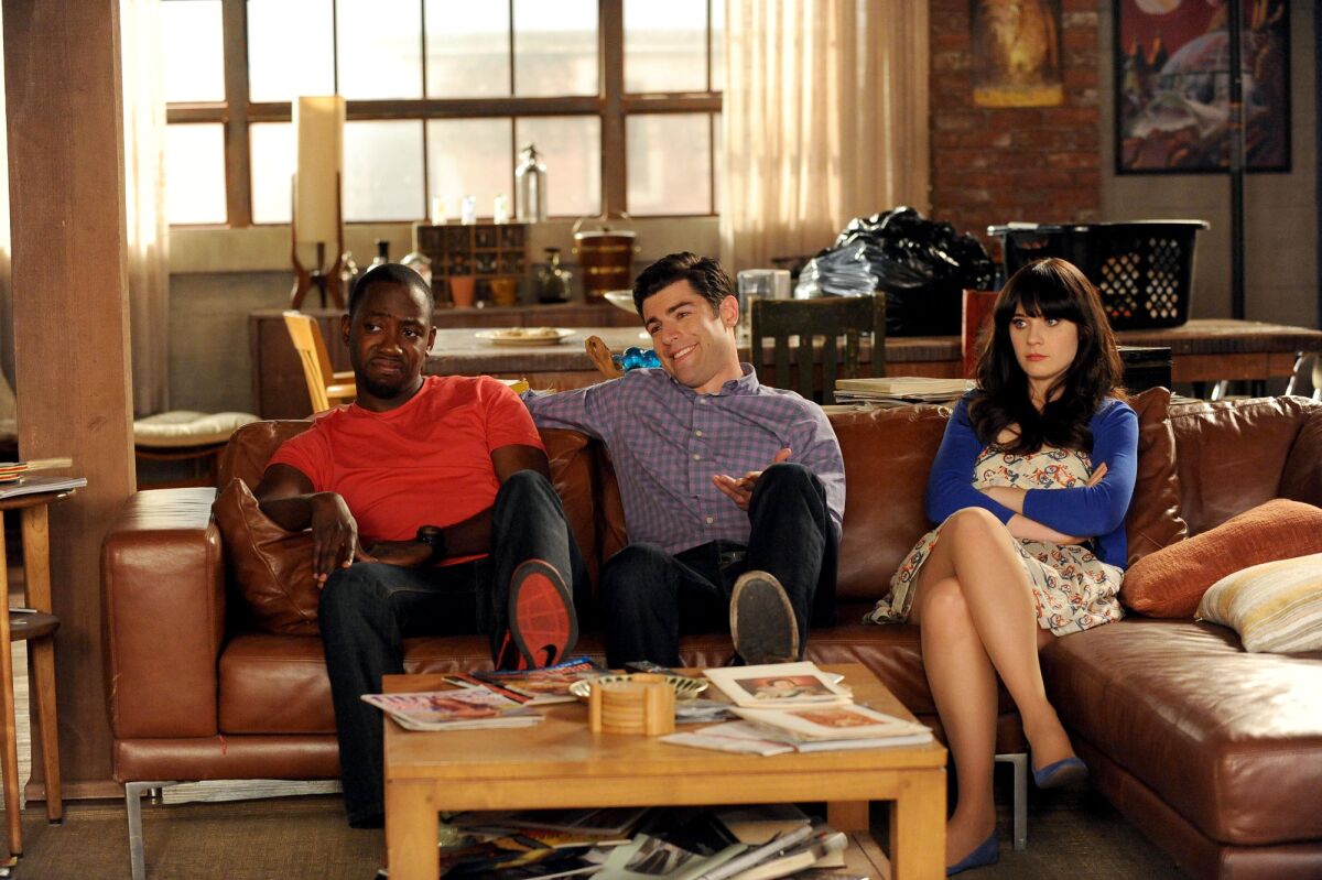 Three people sit on a couch in a living room.