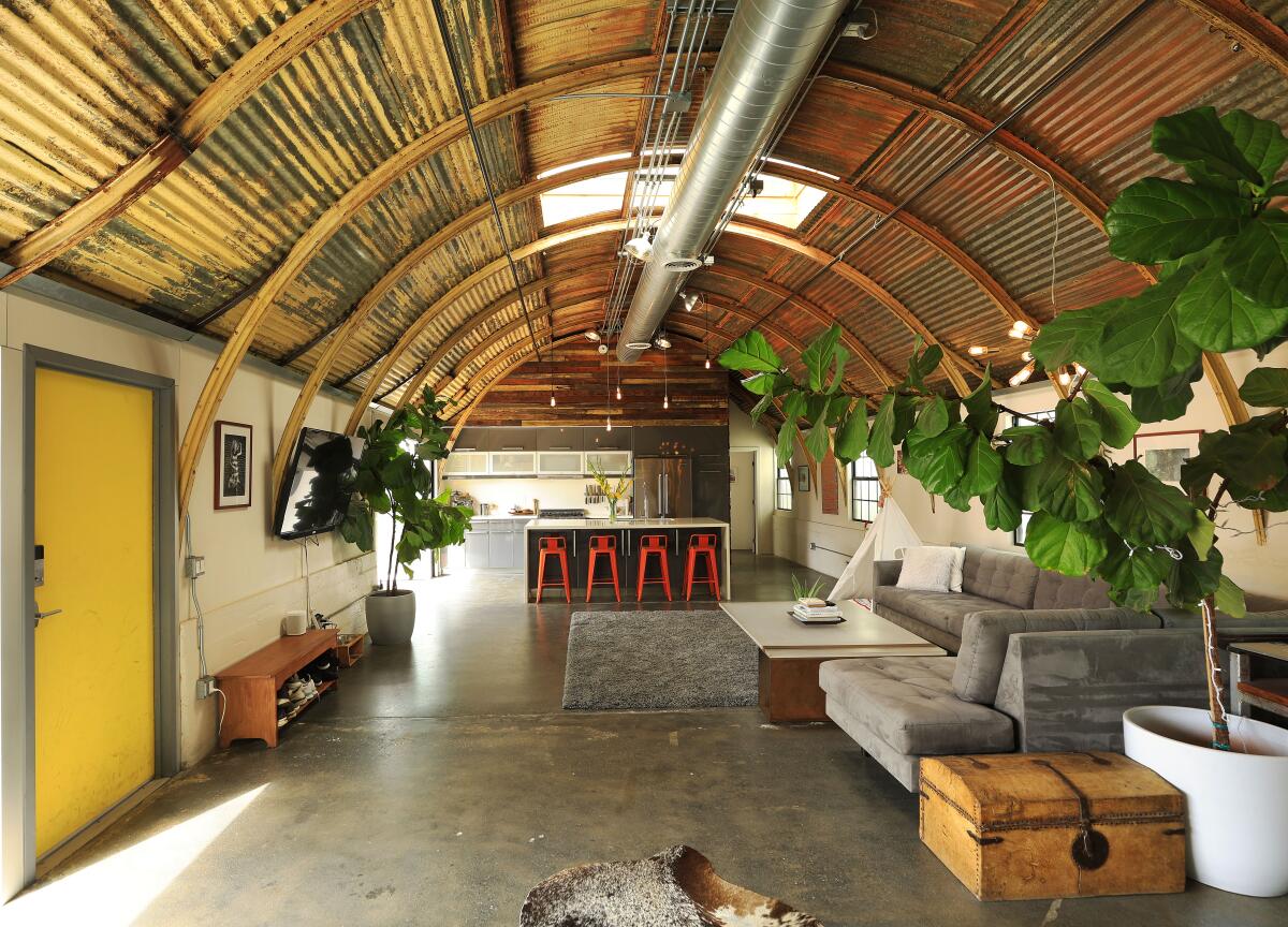 A kitchen and living area's muted colors showcase the patina of the World War II-era Quonset hut converted into a home.