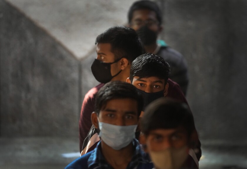 Children wait to receive their vaccination for COVID-19 at a government school in New Delhi, India, Monday, Jan. 3, 2022. Indian health authorities Monday began vaccinating teens in the age group of 15 to 18, as more states started to enforce tighter restrictions to arrest a new surge stoked by the infectious omicron variant. (AP Photo/Manish Swarup)