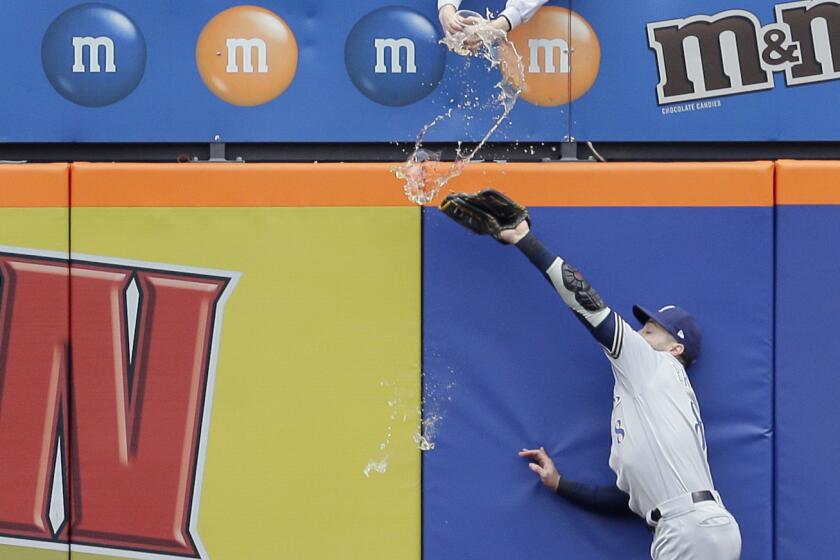 A fan spills beer on Milwaukee Brewers left fielder Ryan Braun as he tries but fails to grab a triple hit by New York Mets' Pete Alonso during the first inning of the MLB baseball game at Citi Field, Sunday, April 28, 2019, in New York. (AP Photo/Seth Wenig)