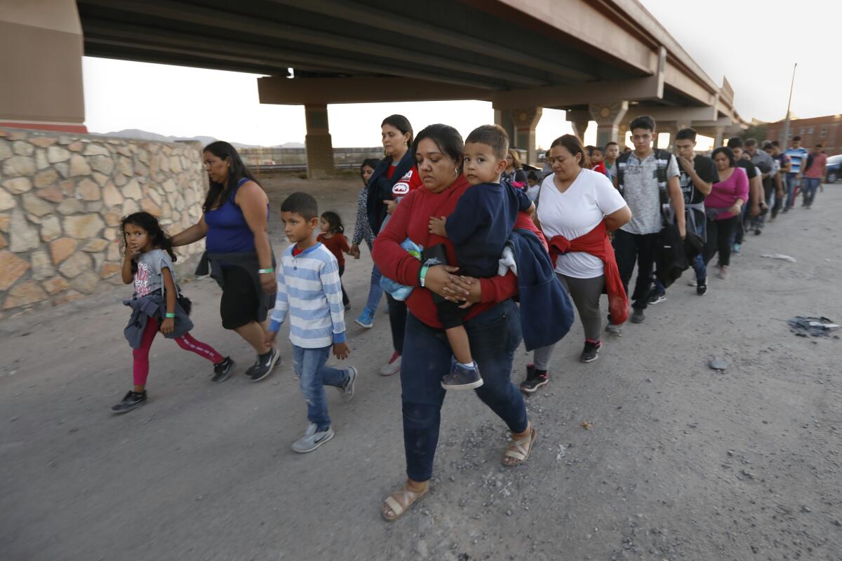 Dozens of men, women and children walk in a long column