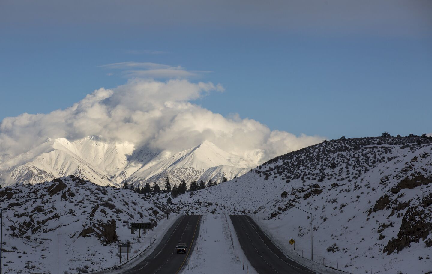 A break in a series of storms moving across California highlights the snow-covered White Mountains looming over U.S. Highway 395 in Crowley Lake.