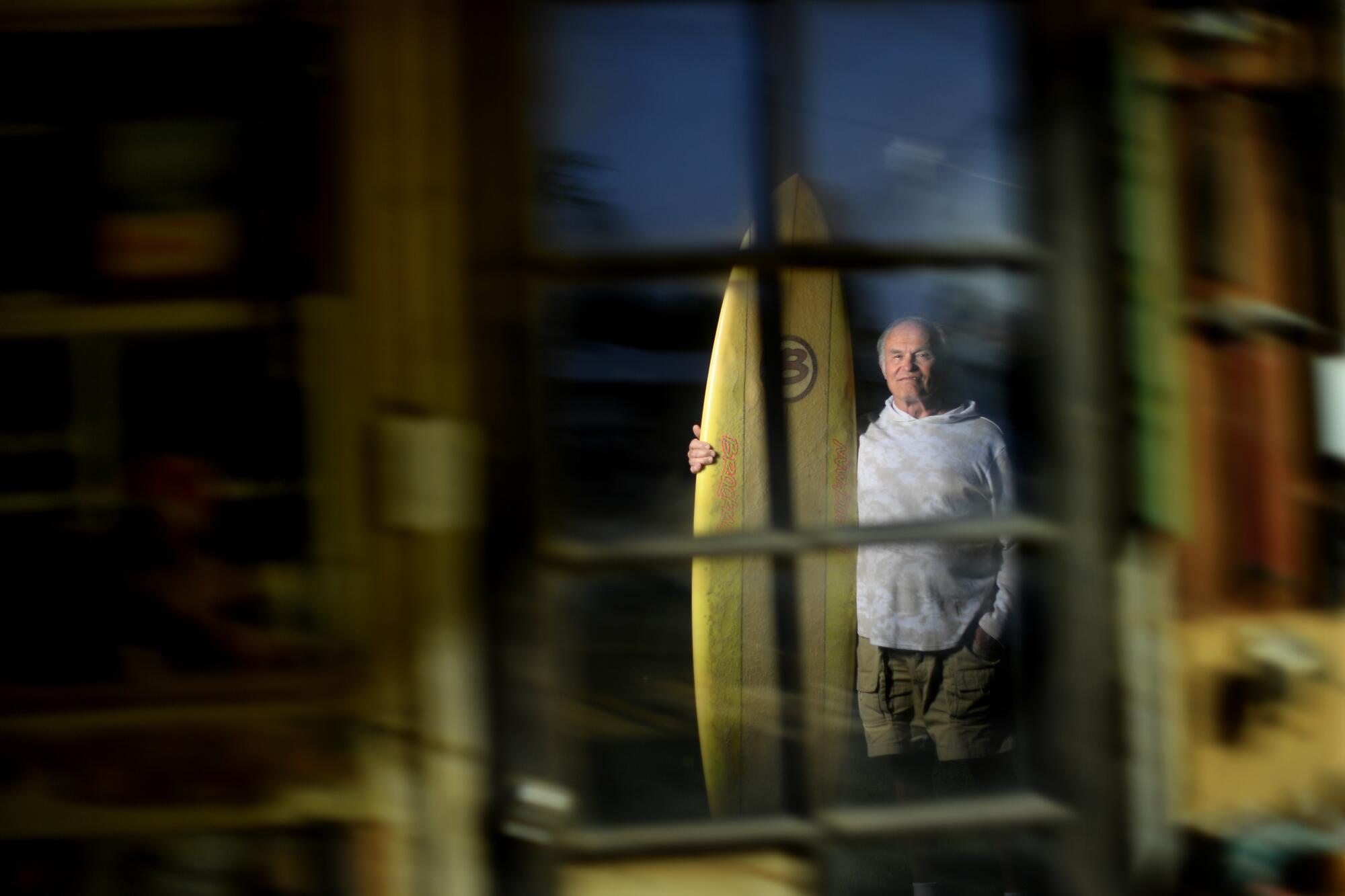 Surfer Bob Levy in his back yard in Long Beach with one of his surfboards.