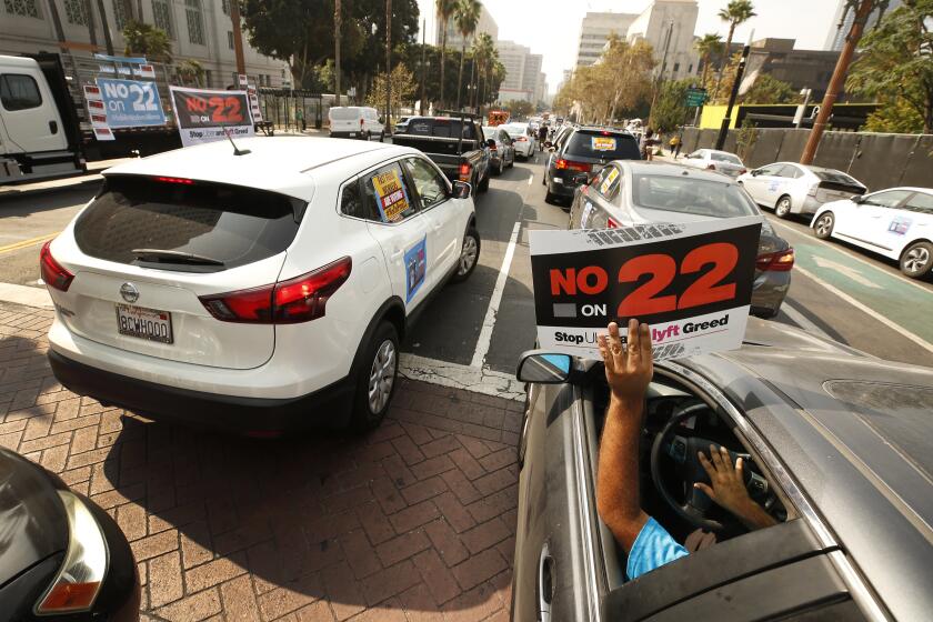 LOS ANGELES, CA - OCTOBER 08: Rideshare driver Jorge Vargas raises his No on 22" sign in support as app based gig workers held a driving demonstration with 60-70 vehicles blocking Spring Street in front of Los Angeles City Hall urging voters to vote no on Proposition 22, a November ballot measure that would classify app-based drivers as independent contractors and not employees or agents, providing them with an exemption from California's AB 5. The action is part of a call for stronger workers' rights organized by the Mobile Workers Alliance with 19,000 drivers in Southern California and over 40,000 in all of California. Los Angeles on Thursday, Oct. 8, 2020 in Los Angeles, CA. (Al Seib / Los Angeles Times
