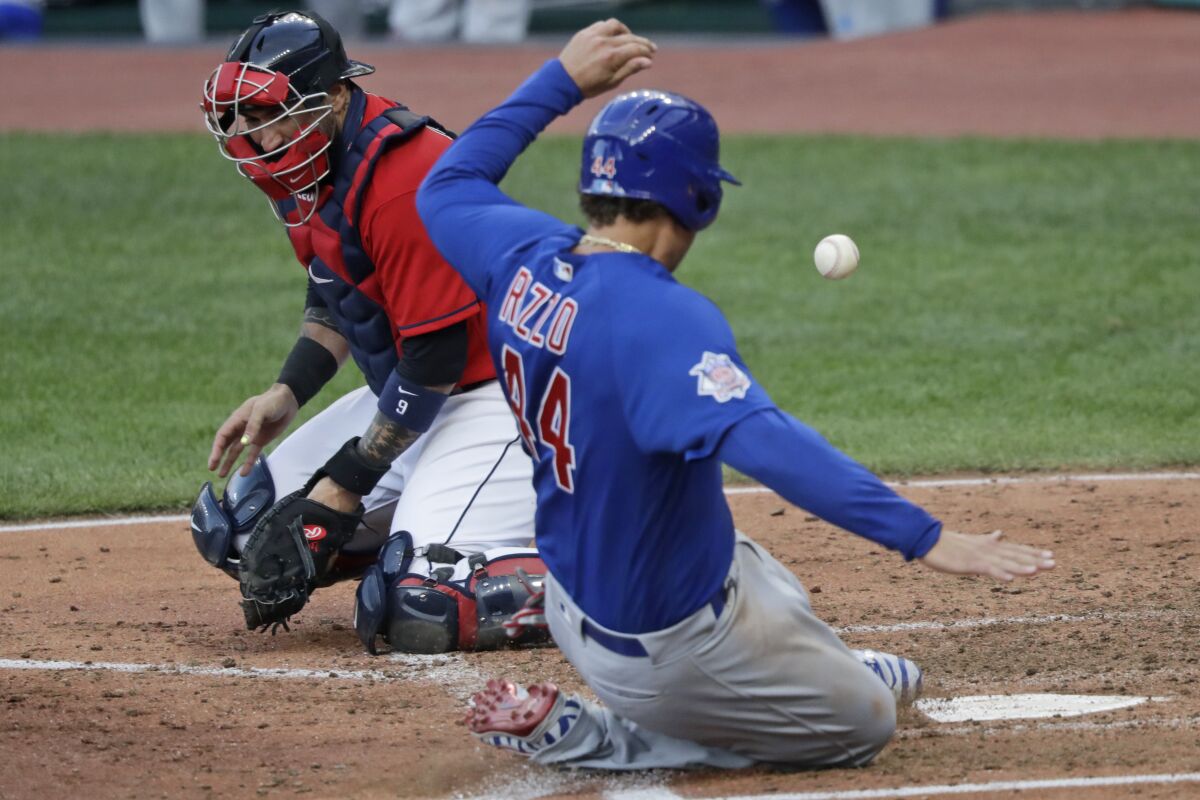 Chicago Cubs' Anthony Rizzo, right, scores as Cleveland Indians catcher Sandy Leon can't hold onto the ball in the fifth inning in a baseball game, Wednesday, Aug. 12, 2020, in Cleveland. (AP Photo/Tony Dejak)