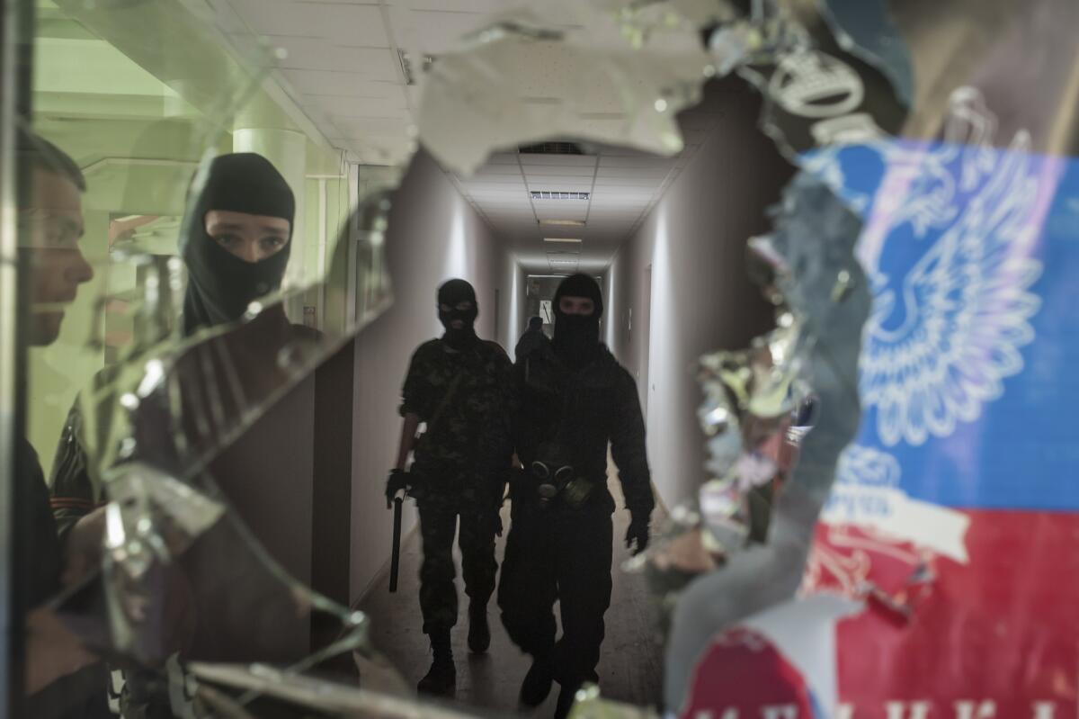 Pro-Russia separatists, as seen in this April 26 photo occupying the Mariupol city administration building, have been driven out of the eastern Ukrainian port by police patrols bolstered by steelworkers from oligarch Rinat Akhmetov's industrial empire.