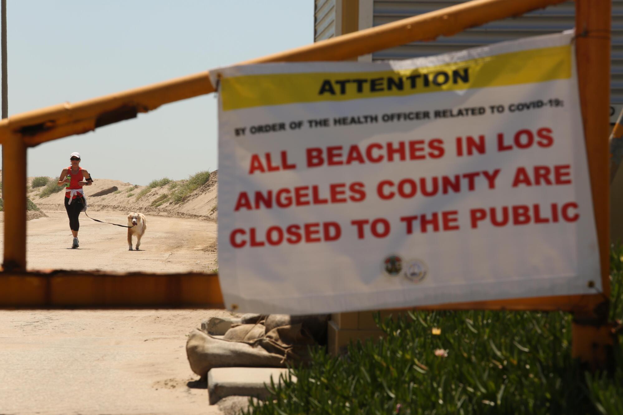 A jogger and her dog run on a closed road at Westward Beach in Malibu. The beach has been temporarily closed in an effort to help stop the spread of the coronavirus.