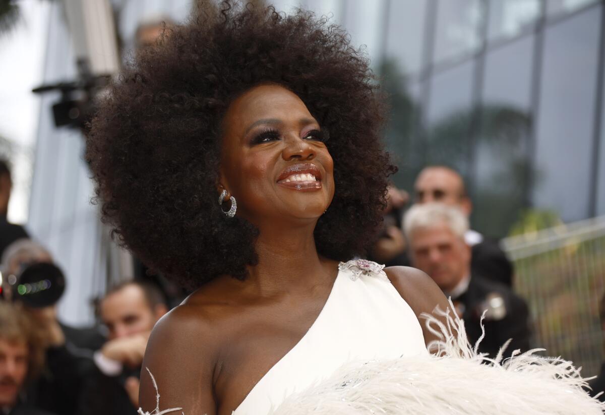 Viola Davis smiling in a white fuzzy dress and sparkly earrings.