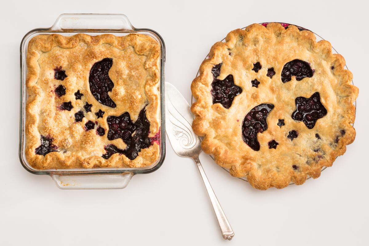 Two blueberry pies, one round and one square, with moons and stars cut out of the top crusts