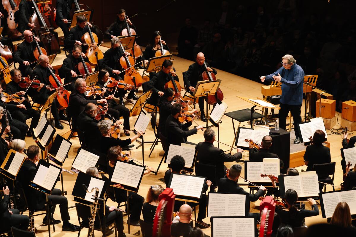 Michael Tilson Thomas, in a blue sweater, leads the L.A. Phil from the conductor's podium.