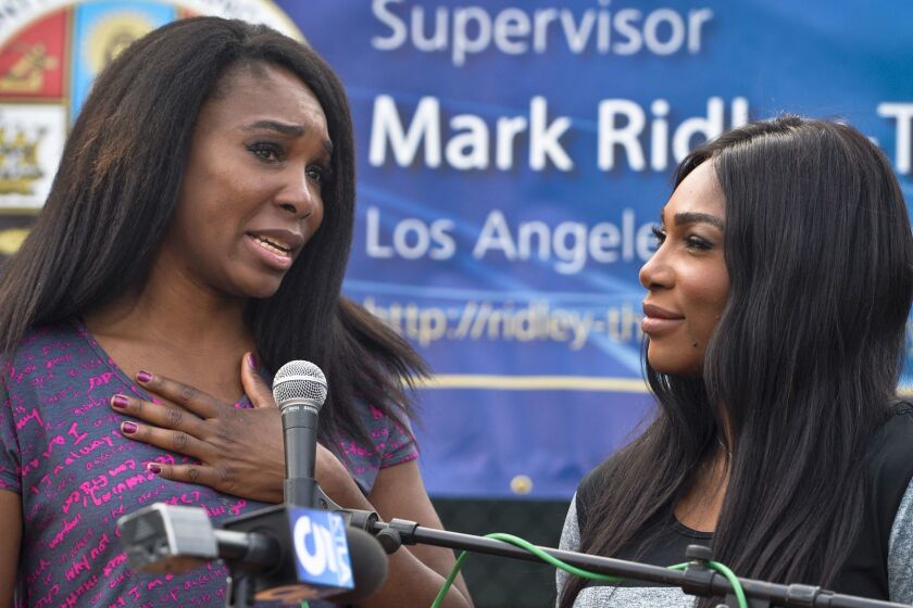 Venus Williams, left, and sister Serena Williams speak at the opening ceremony for new tennis courts at East Rancho Dominguez County Park in Compton.