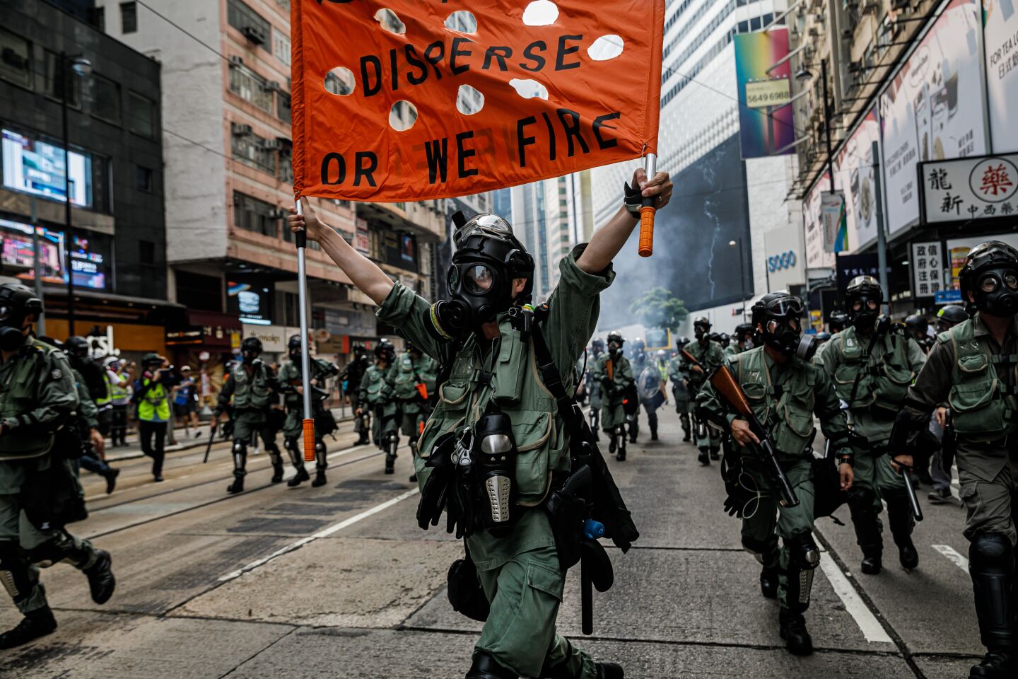 Hong Kong police officers in riot gear raise warning flags as they use tear gas to disperse demonstrators, gathering in defiance of the upcoming China's national day, in Causeway Bay area of Hong Kong, on Sept. 29, 2019.