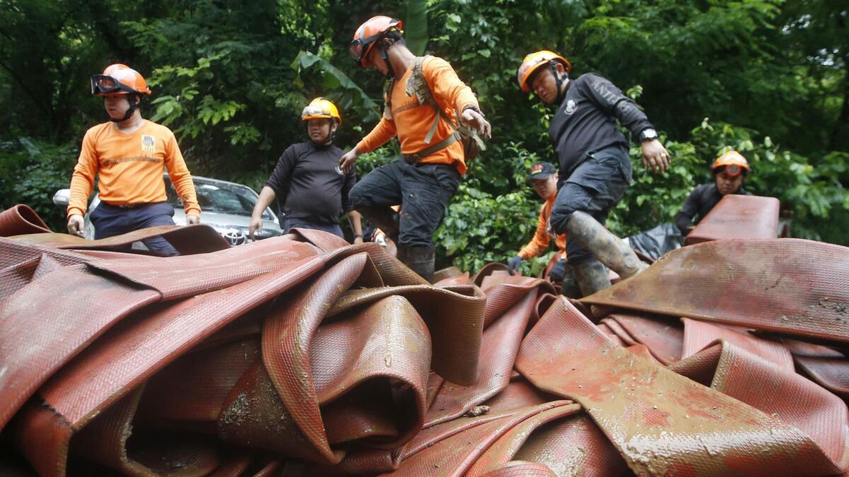 Rescue personnel arrange large hoses and water pumps as part of a search operation for a young soccer team and their coach in a large flooded cave on Thursday.
