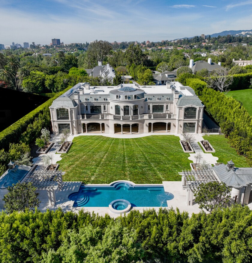 Aerial view of the backyard of a mansion with a sprawling lawn and a swimming pool