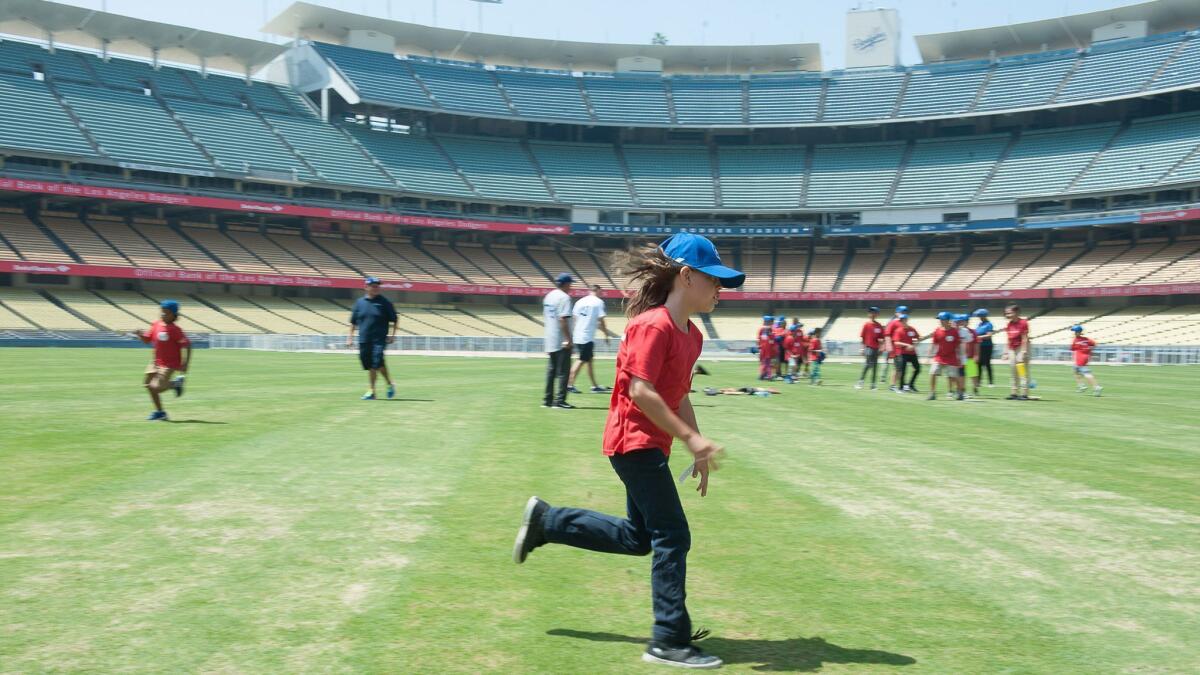 Sammy Tello runs in the outfield of Dodger Stadium during base running drills Wednesday as part of Bank of America's annual youth baseball clinic, held in part with the Dodgers.