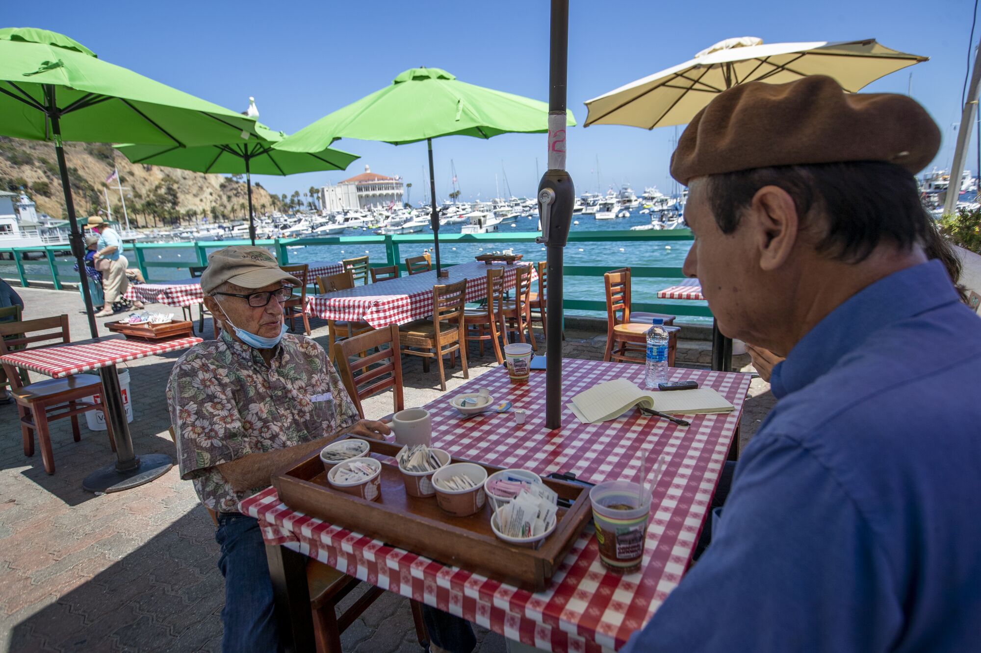 David Sanchez, right, talks to Catalina Island resident Rudy Piltch outside at a restaurant in Avalon.