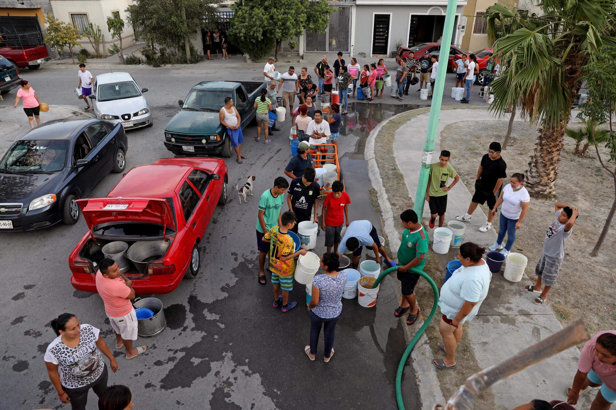 A street scene as neighbors gather to fill containers with water