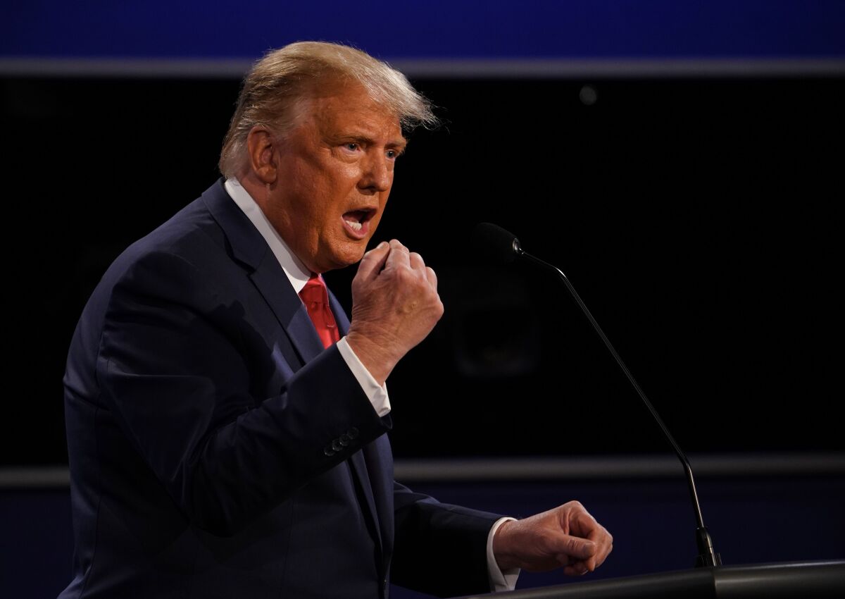 President Trump curls his right hand into a fist while speaking onstage at the debate