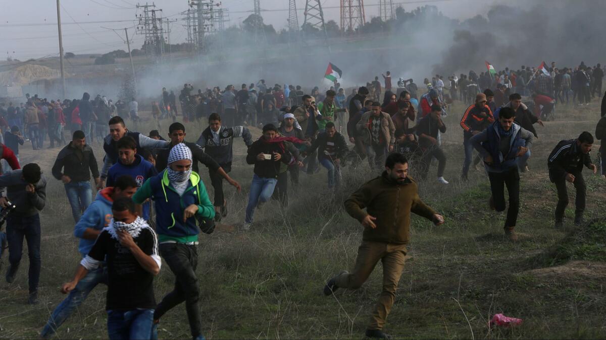 Palestinian protesters run for cover from teargas fired by Israeli soldiers east of Gaza City on Friday during clashes on the Israeli border following a protest against President Trump's decision to recognize Jerusalem as the capital of Israel.