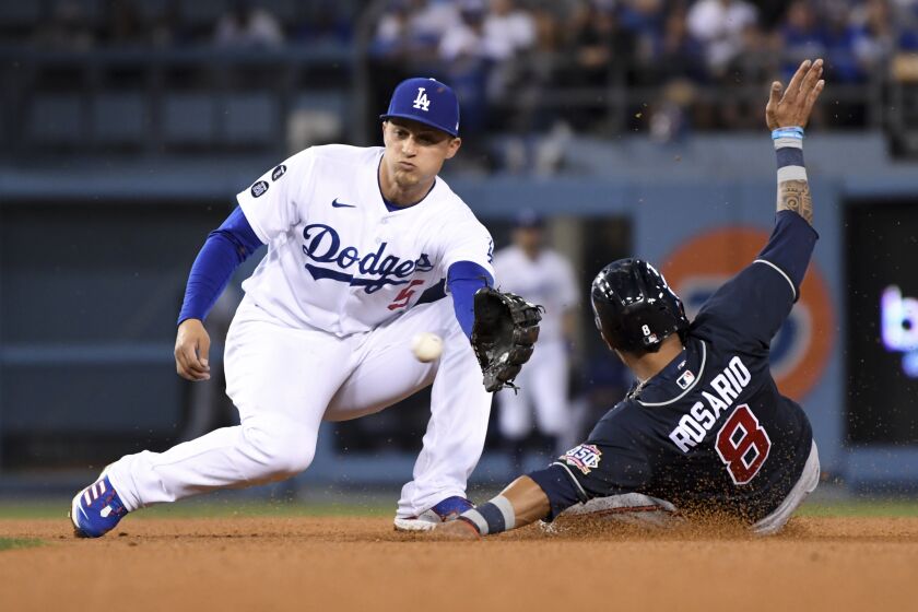 Los Angeles, CA - October 21: Los Angeles Dodgers shortstop Corey Seager, left, prepares to catch a ball while Atlanta Braves' Eddie Rosario attempts to steal second during the third inning in game five in the 2021 National League Championship Series at Dodger Stadium on Thursday, Oct. 21, 2021 in Los Angeles, CA. (Wally Skalij / Los Angeles Times)