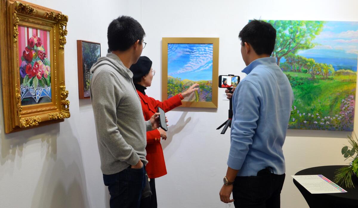Artist Young Sook Shin talks about her "Quail Hill Walk" painting to grandsons James and Justin Koga.