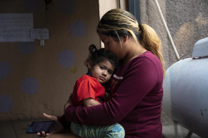 Tijuana , Baja California - May 10: Nicolle Urbina, 20, holds her daughter Marlexy Martinez, 1, who came down with a cold the night before at Espacio Migrante on Wednesday, May 10, 2023 in Tijuana , Baja California. Urbina, her husband and their two children are from Honduras and have been staying at the shelter for several months while trying to get an appointment to request asylum in the United States by using the CBP One smartphone app. Many users have complained about the application having errors. Title 42 was put in place by the Trump administration in March 2020 based on a public health order that was used to block migrants from entering the United States. The policy is expected to end at 11:59 p.m. Thursday. (Ana Ramirez / The San Diego Union-Tribune)